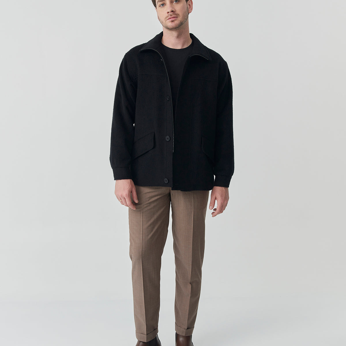 Man wearing a black baby alpaca jacket with front buttons and flap pockets.