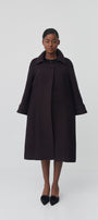 Person wearing a black coat on a white background