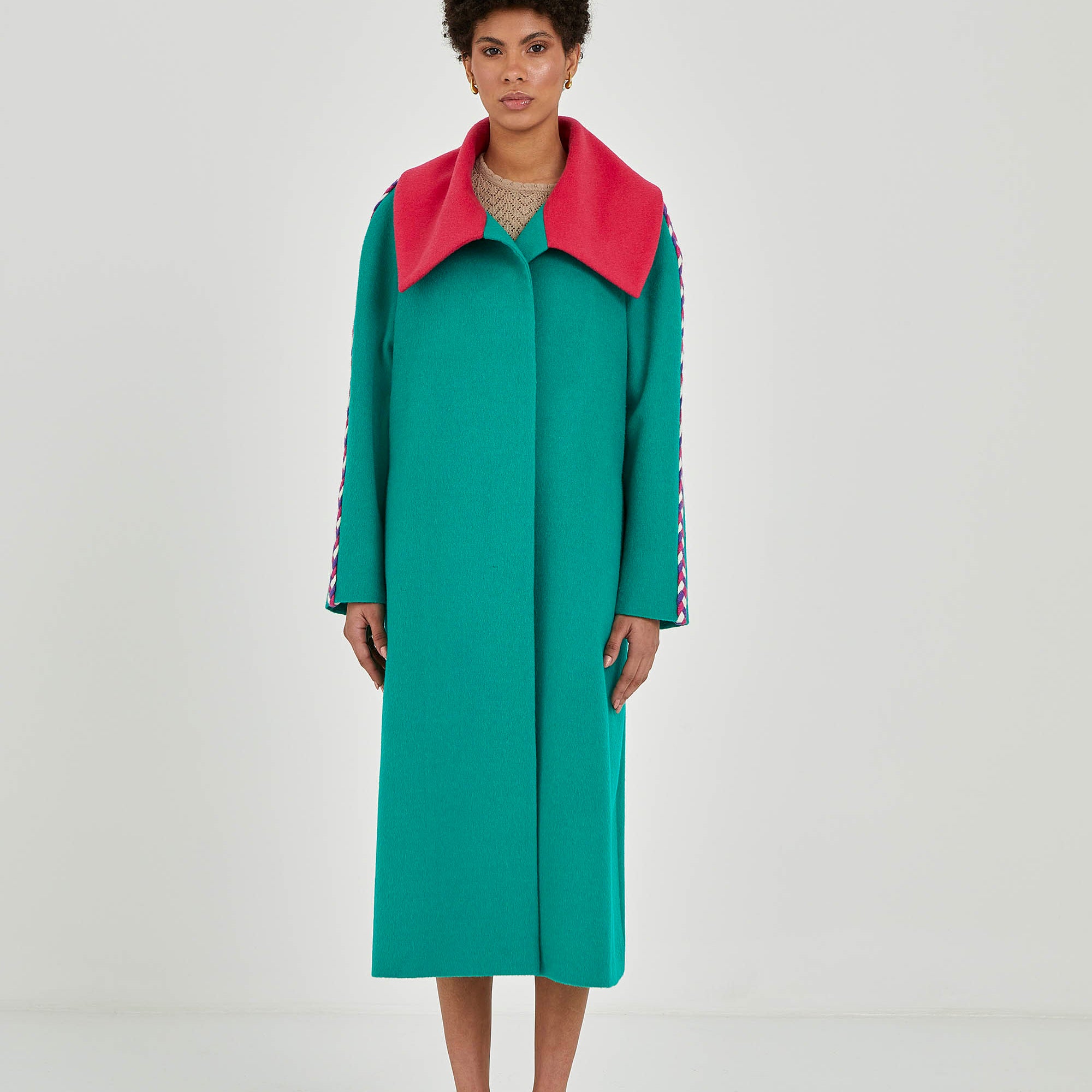Woman wearing a teal Baby Alpaca coat with a contrasting collar and a detail on the sleeves.