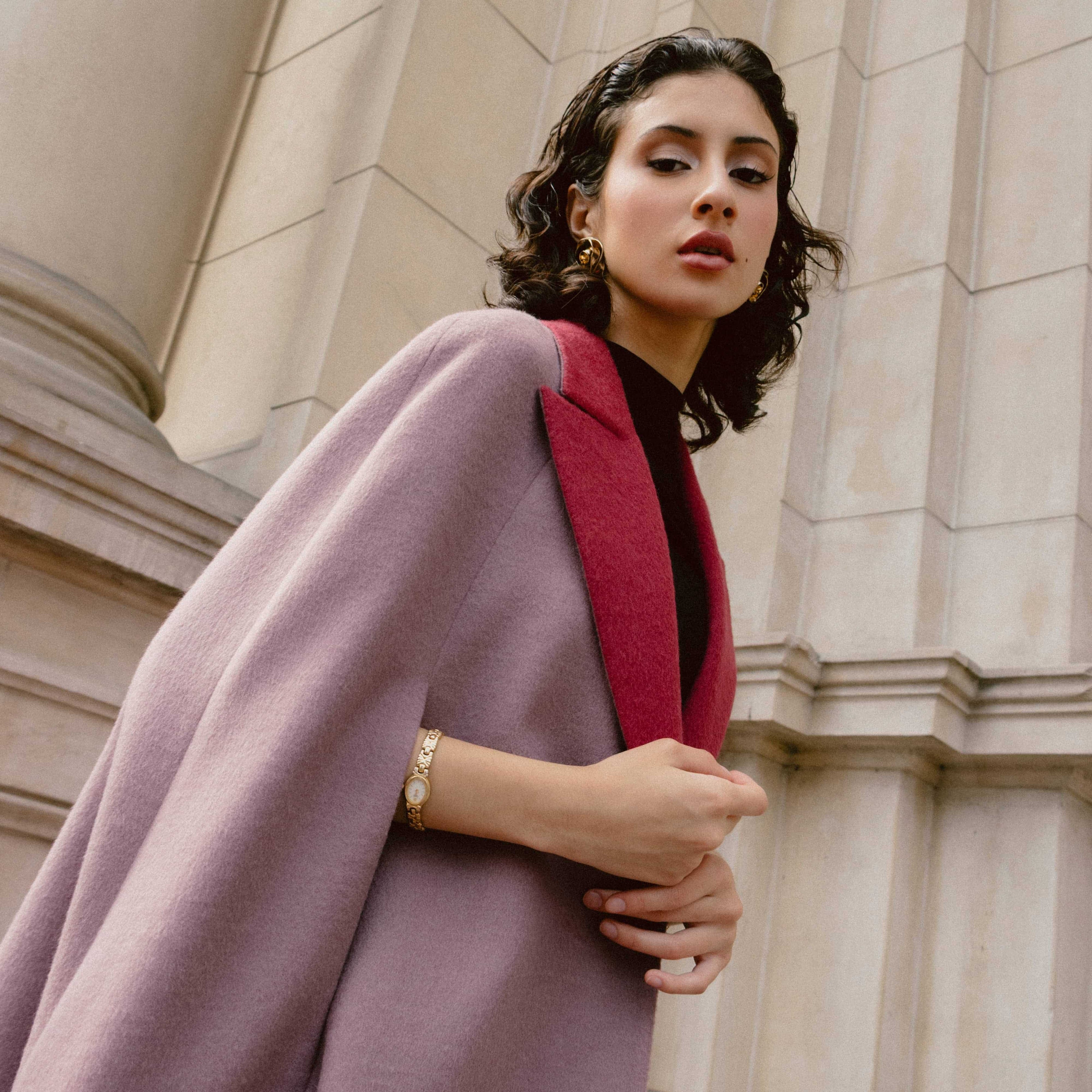 A woman wearing a light purple baby alpaca cape-style coat with a red collar.