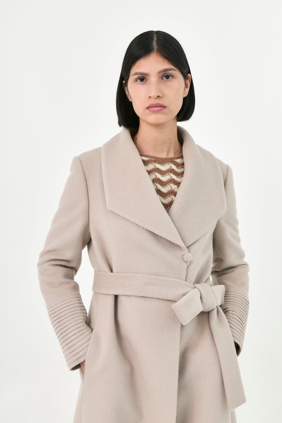 A model wearing a light beige baby alpaca belted coat 