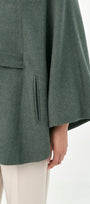 Close-up of a green baby alpaca cape with side pockets and a belt.