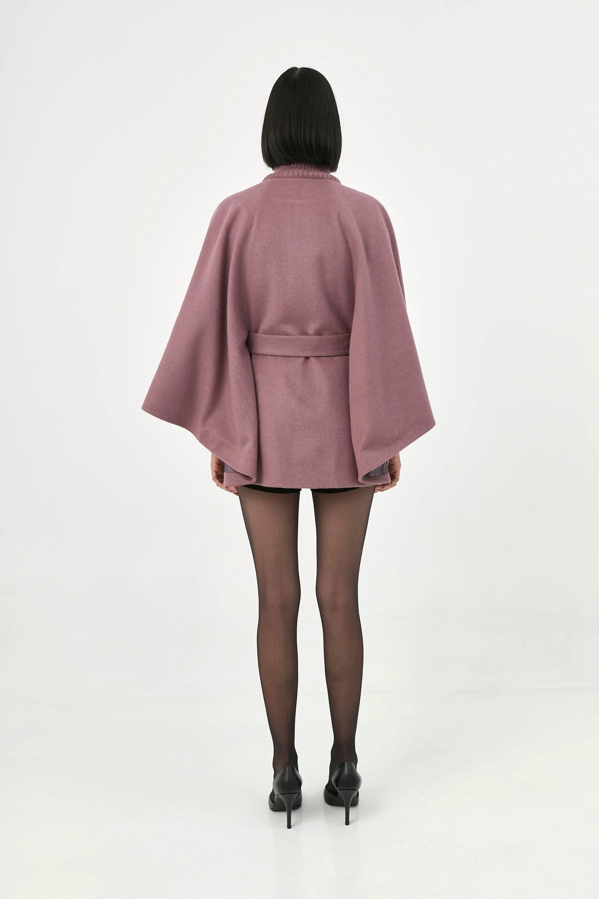 A model viewed from the back wearing a rose mauve baby alpaca belted cape.