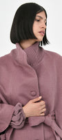 A model wearing a rose mauve baby alpaca belted cape with a ribbed turtleneck collar.