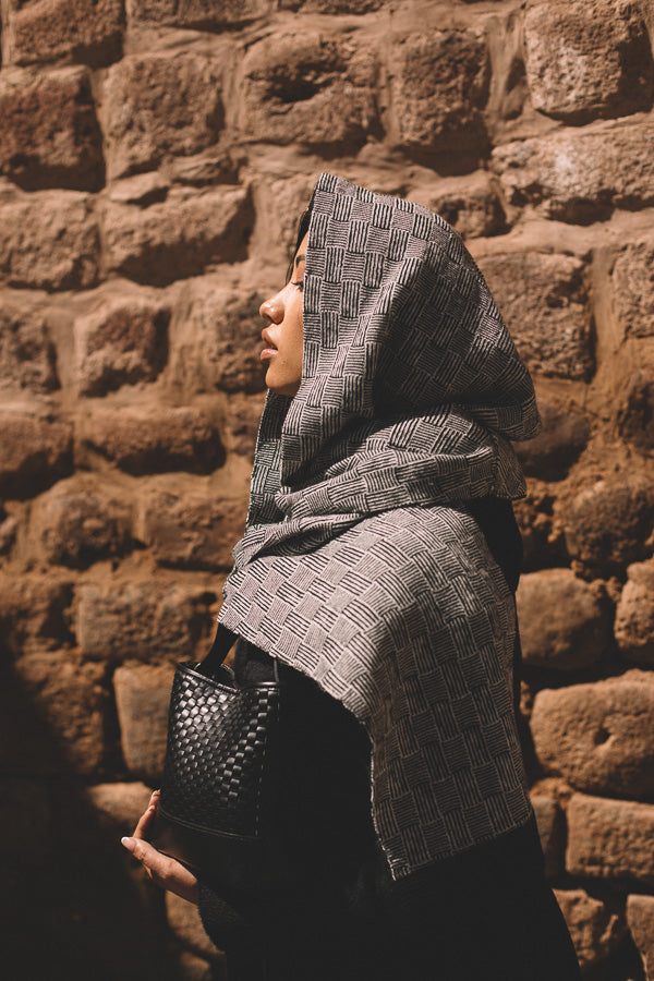 Person wearing a gray patterned shawl crafted in baby alpaca